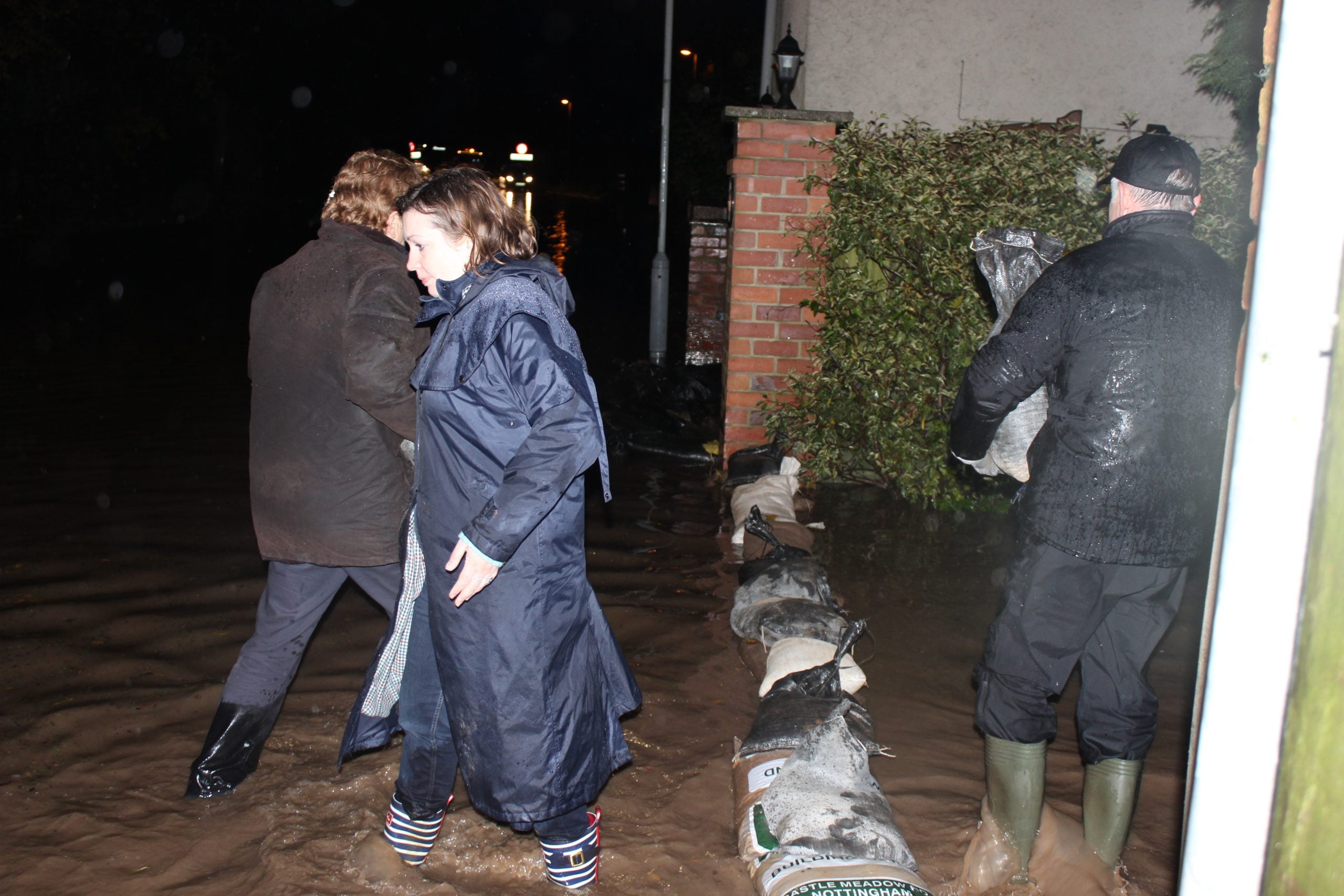 Ruth knee deep in flood water placing sand bags in Tollerton