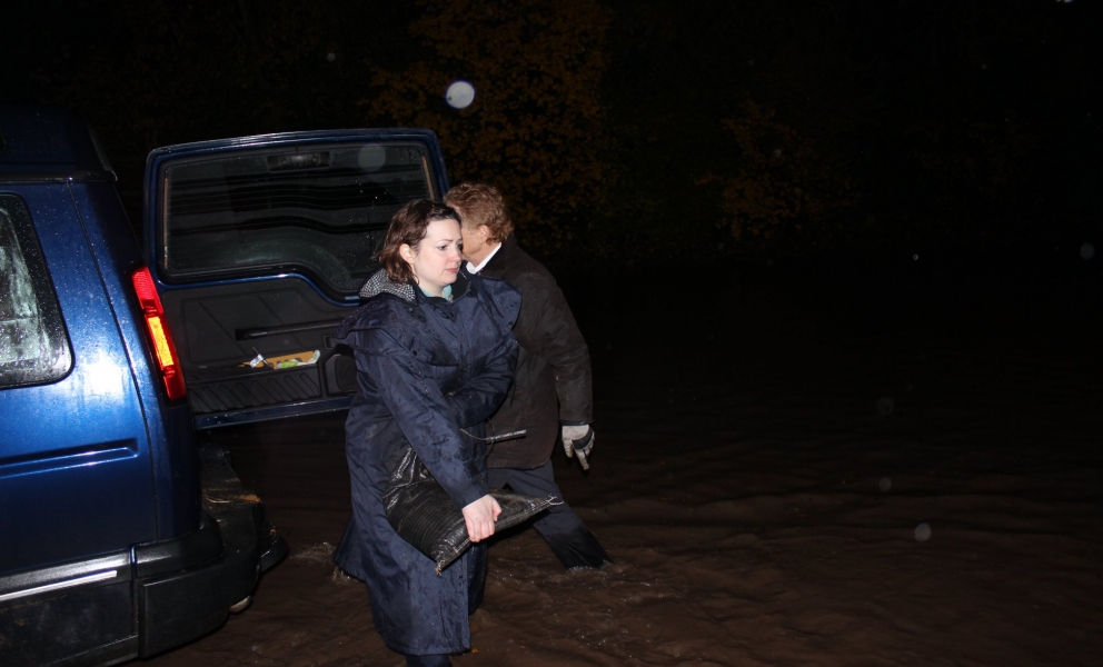 Ruth carrying a sandbag knee deep in floodwater in Tollerton
